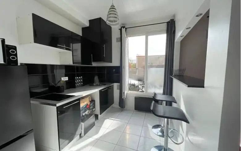 La cuisine et son bar, côté fenêtre — Appartement T1 de 21m² à Alfortville