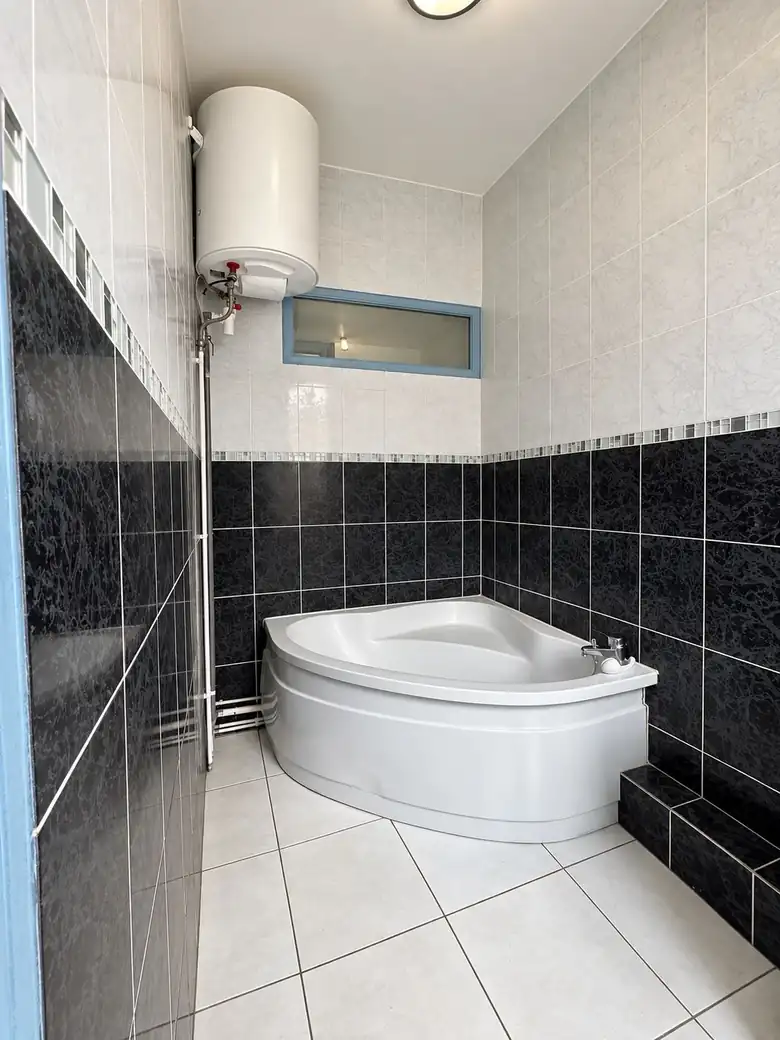 La salle de bains, faïence marbrée noire et baignoire d’angle — Immeuble de rapport de 143m² composé de 2 appartements à Saint-Pol-sur-Mer